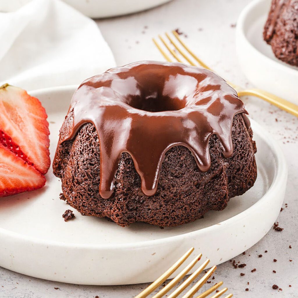 Mini chocolate bundt cake with glossy chocolate glaze and fresh strawberries.