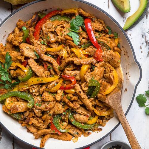 Colorful stir-fried chicken with vegetables in a skillet.