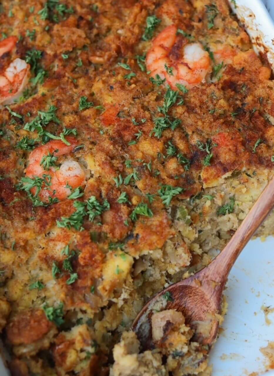 Close-up of a cheesy baked shrimp casserole garnished with herbs.