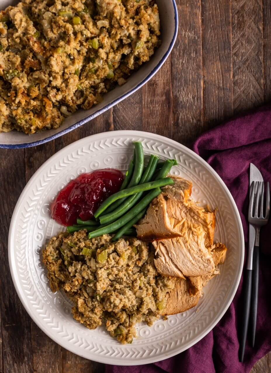 A Thanksgiving plate with turkey, stuffing, green beans, and cranberry sauce.