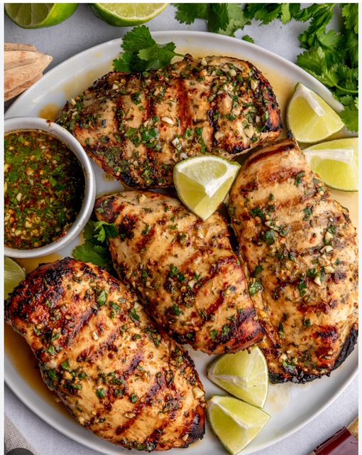 Grilled chicken breasts served with lime wedges and dipping sauce.