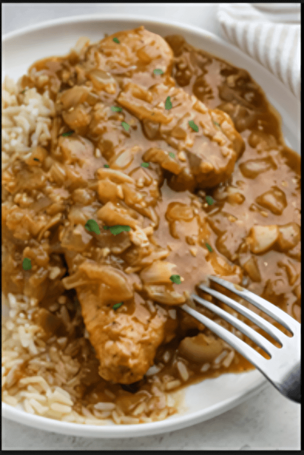 Chicken with gravy and rice on plate.