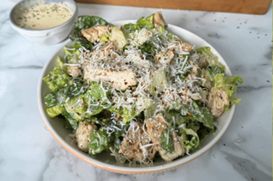 Caesar salad with chicken and grated cheese.